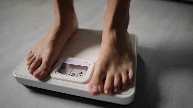 Woman bare feet stepping on a floor scale to measure body weight