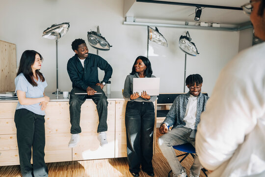 Group of male and female computer programmers talking with each other at office