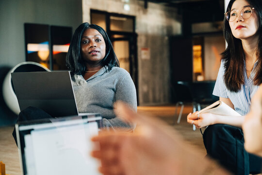Businesswoman interacting with team during meeting at office