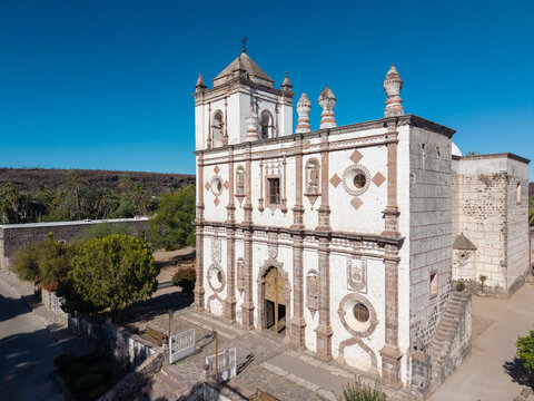 View of Mission Church in San Ignacio oasis showing the historical building and landscape under clear blue sky in Baja California