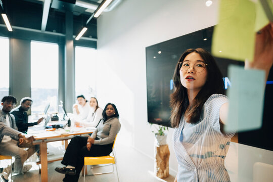 Young female employee leading creative meeting with team at modern startup office