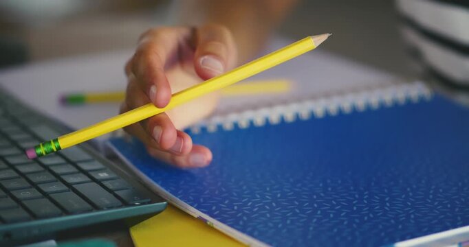 Person Twirling Pencil at Desk in Office Setting