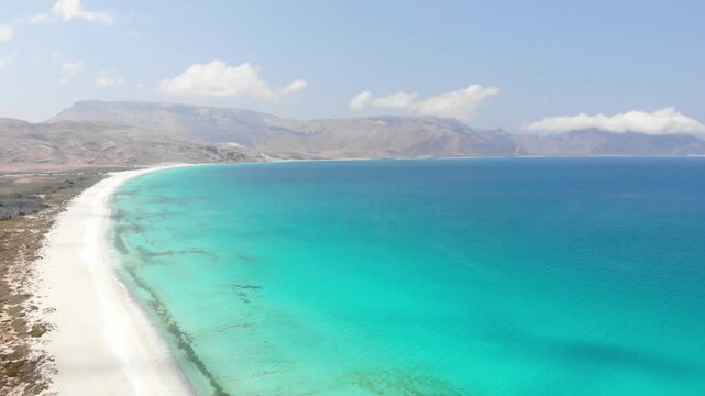 Panoramic aerial video of Socotra Island's rugged coastline, where desert cliffs meet the turquoise ocean, perfect for travel and adventure footage