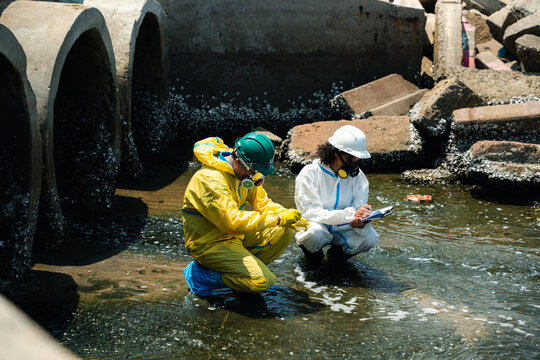 Hazmat workers in protective suits inspecting polluted wastewater drainage tunnel and contaminated industrial water during environmental hazard response operation