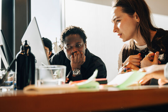 Diverse business colleagues looking closely at computer screen at startup workspace