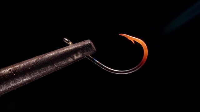 Fishing Hook Heated to Red Hot Glow While Clamped in Tool on Black Background, Macro Close Up with Intense Light, Slow Motion Metal Softening and Heat Treatment Process