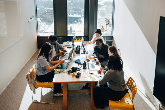 High angle view of colleagues collaborating and sharing ideas during work session at modern office
