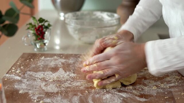 Woman's hands kneading pastry dough on a rolling board to prepare homemade Christmas cookies
