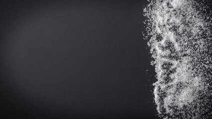 Top view of spilled sugar scattered across deep black background, creating striking contrast and minimalist composition. Large empty copy space for product placement or advertising text.  © magdal3na