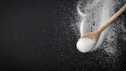 Top view of spilled sugar scattered across deep black background, creating striking contrast and minimalist composition. Large empty copy space for product placement or advertising text.  © magdal3na