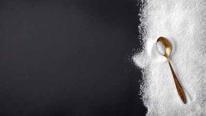 Top view of spilled sugar scattered across deep black background, creating striking contrast and minimalist composition. Large empty copy space for product placement or advertising text.  © magdal3na