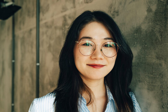 Portrait of smiling young businesswoman leaning on wall at office