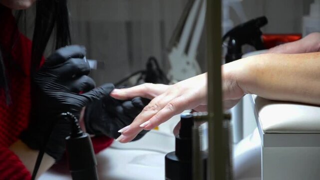 Close-up video of a nail technician performing a professional manicure on a client in a modern beauty salon.