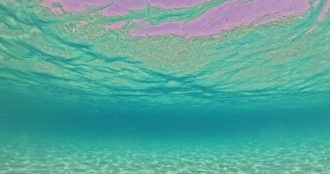 Underwater view of turquoise crystal clear sea water with sun rays splashing waves