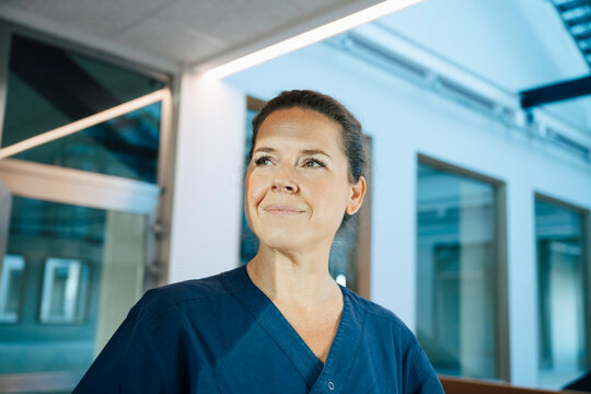 Contemplative female doctor looking away while standing in hospital corridor