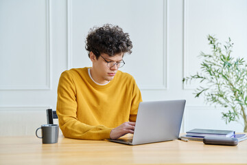 University student guy typing on computer studying at a desk with laptop