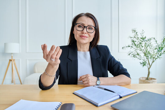 Professional mature woman in glasses talking directly to camera during a virtual meeting