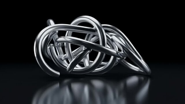 A tangled mass of metal wires lies on a reflective surface in darkness.