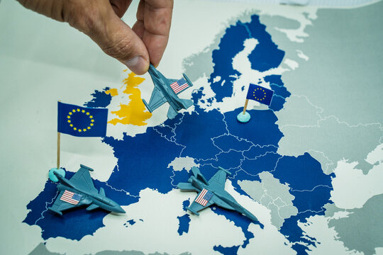 Hand moving toy US fighter jets on a map of Europe, illustrating troop withdrawal, geopolitical strategy, and international relations between the United States and European nations
