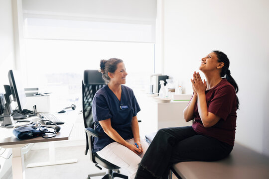 Happy female healthcare professional sitting near woman showing gratitude after hearing good news in hospital