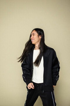 Smiling non-binary person looking away while standing against colored background