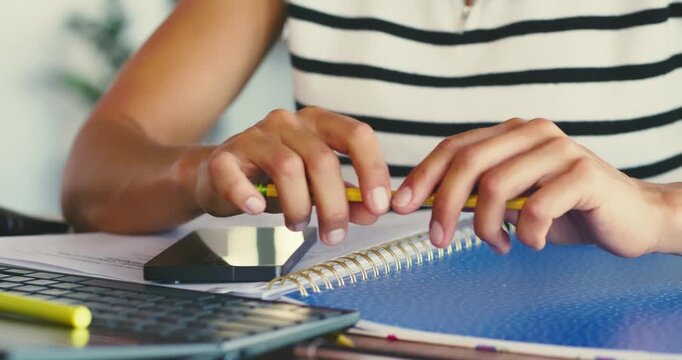 Person Tapping Pencil on Notebook at Desk