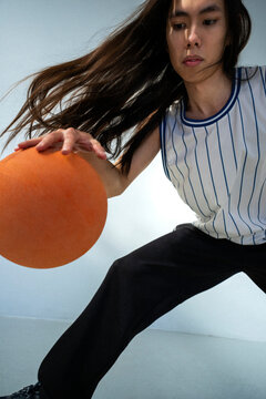 Determined non-binary person dribbling with basketball