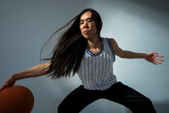 Portrait of confident non-binary basketball player against colored background