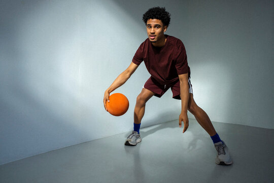 Full length portrait young man practicing basketball skills near wall