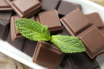 Pieces of yummy chocolate and mint leaves on table, closeup © New Africa