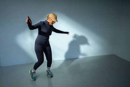 Full length of happy senior woman dancing in front of wall