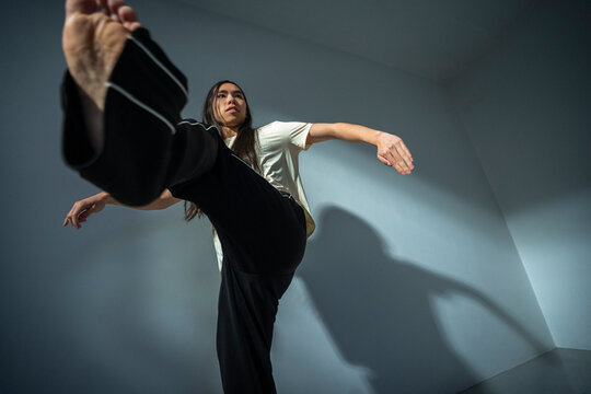 Low angle view of determined non-binary person practicing contemporary dance near wall