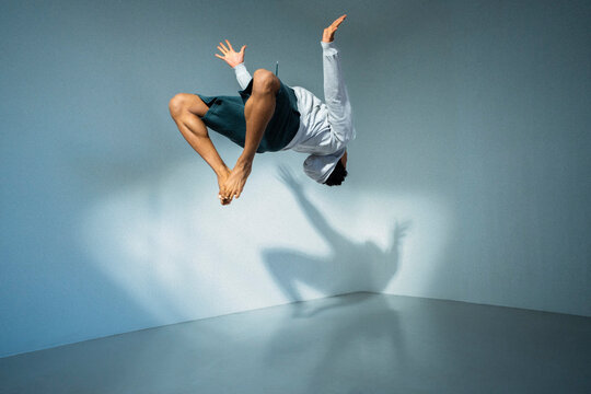 Full length view of young man performing backflip in front of wall