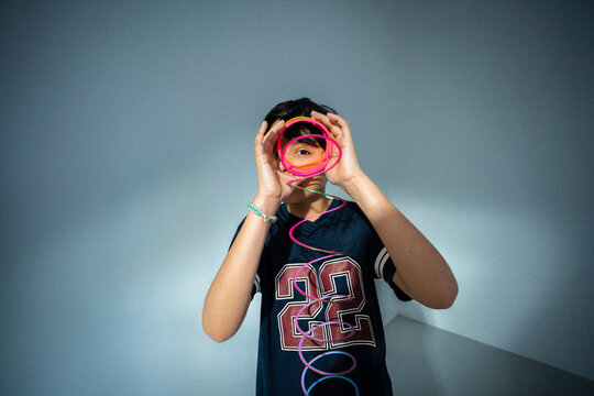 Portrait of boy wearing number 22 jersey playing with spiral toy against wall
