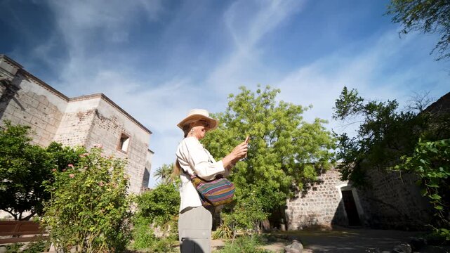 Mature woman takes pictures and enjoys her time at Mission Church in San Ignacio, Baja California. She appreciates the local sights.