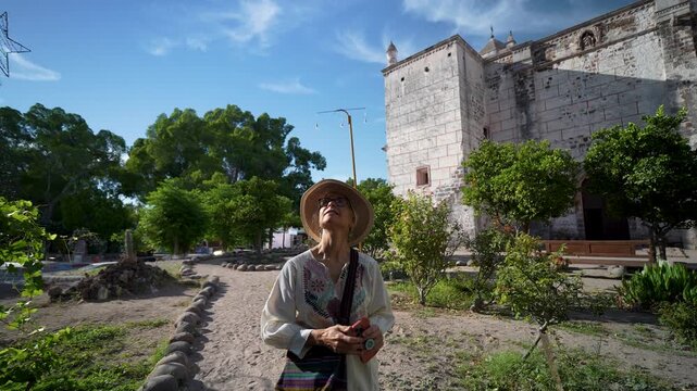 Mature woman explores Mission Church in San Ignacio Baja California enjoying the sights and taking pictures on a bright day.