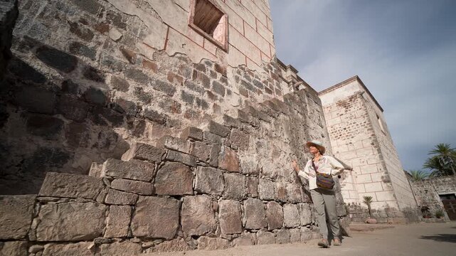 Mature woman takes in the sights of Mission Church in San Ignacio, Baja California Sur, while experiencing the local culture and history.