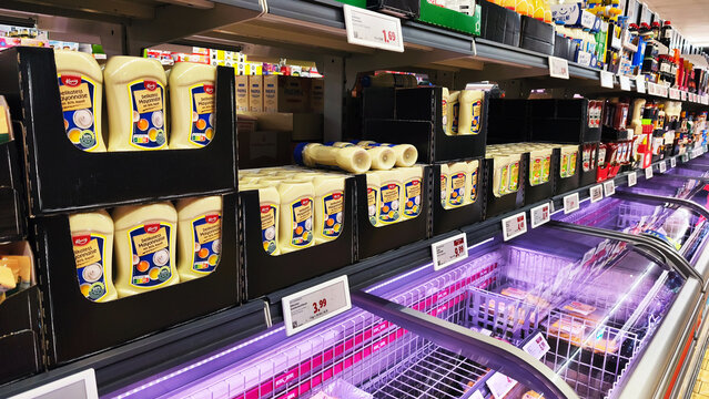 Iserlohn, Germany &mdash; May 06 2026: supermarket shelves at Lidl showing price tags and a large stock of Kania Delikatess Mayonnaise bottles above freezer units.