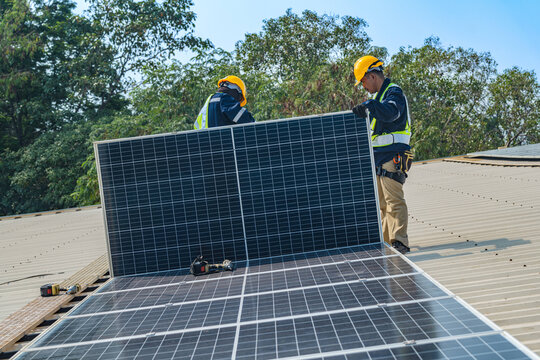 Wide shot of a professional solar installation team efficiently placing and securing panels on a large-scale industrial warehouse roof.