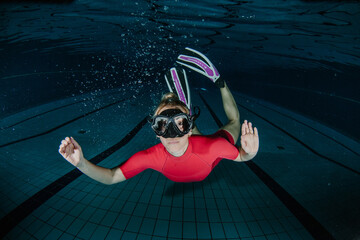 Female diver in a red swimsuit and full scuba gear swimming freely in clear blue water, experiencing stillness and tranquility © Zamrznuti tonovi
