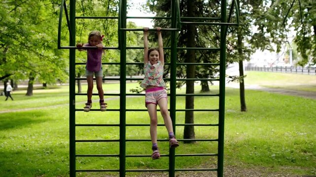 Two little girls is engaged on horizontal bars