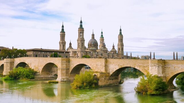 stone bridge crossing ebro river with basilica of our lady of the pillar in zaragoza spain