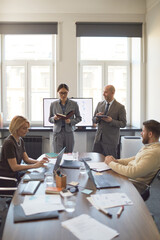 Fototapeta premium Business team discussing strategy during office meeting, Asian young woman presenting notes while colleagues reviewing data. Ideal for corporate training, teamwork, management