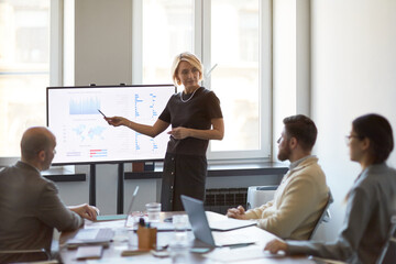 Businesswoman presenting sales data on monitor during team meeting, discussing strategy and...