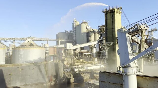 big clouds of grain dust moved by wind from the ship to the berth. industrial waterfall from tower make wall of water and protect the berth. at same time it is good food for fish.