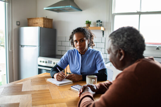 Home nurse consulting with senior man at kitchen table