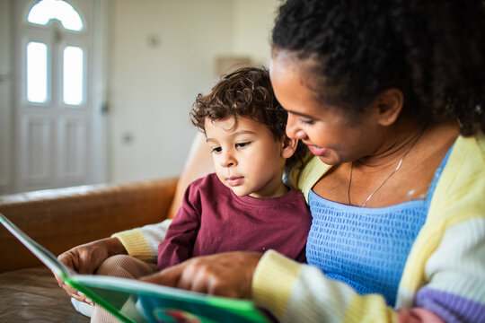Mother reading picture book with son at home