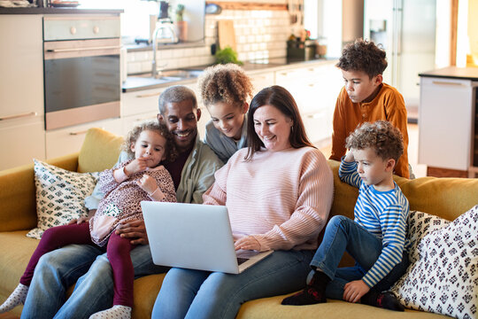 Happy family using laptop together on living room sofa at home