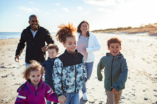 Smiling parents and children walking together on a sunny beach