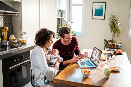 New parents on telehealth call with pediatrician in kitchen